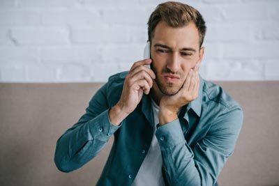 man calling the dentist to help with his tooth pain